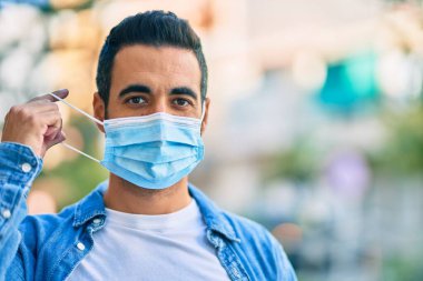 Genç İspanyol adam şehirde dikilerek tıbbi maske takıyor..