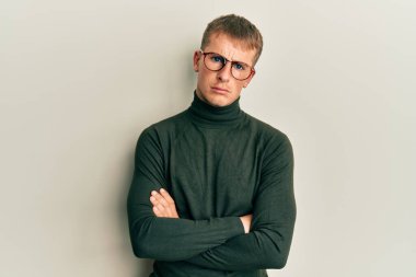 Kollarını kavuşturmuş gözlük takan beyaz bir genç bunalımlı ve üzüntülü, sinirli ve korkmuş bir şekilde ağlıyor. hüzünlü ifade. 