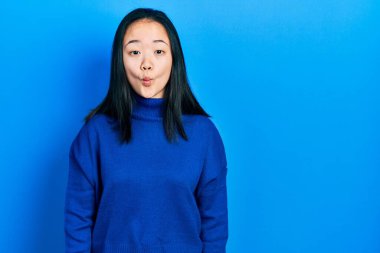 Gündelik kıyafetler giyen genç Çinli kız dudaklarıyla balık suratı yapıyor, çılgınca ve komik bir jest. Komik ifade. 