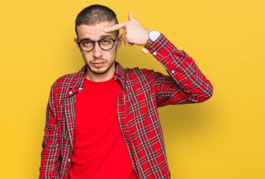 Alnındaki sivilceden mutsuz olduğunu gösteren gündelik kıyafetler giyen İspanyol genç bir adam, siyah başlıklı çirkin bir enfeksiyon. sivilce ve deri problemi 