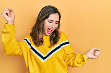 Genç İspanyol kız gündelik kıyafetler giyip dans ediyor mutlu ve neşeli, gülümsüyor rahat ve kendinden emin bir şekilde müzik dinliyor. 