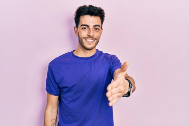 Gündelik tişört giyen genç İspanyol adam dostça bir selamlama ve hoş geldin hediyesi olarak tokalaşıyor. başarılı iş. 