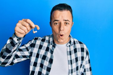 Elinde tıbbi işitme cihazı tutan yakışıklı genç adam ağzı açık kalmış, korkmuş ve hayrete düşmüştü. 