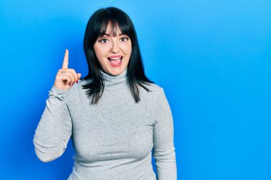 Gündelik kıyafetler giyen genç İspanyol kadın başarılı bir fikri işaret ediyor. Heyecanlı ve mutlu. Bir numara.. 