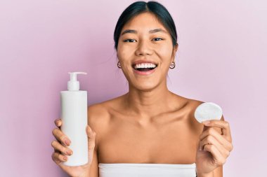 Genç Çinli kadın duş havlusu kullanıyor. Temiz losyon kullanıyor. Gülerek gülüyor.. 