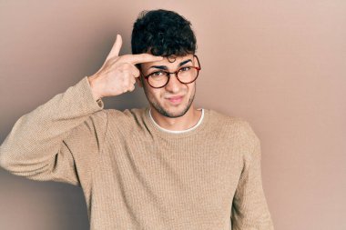 Sıradan kıyafetler ve gözlük takan genç İspanyol adam alnındaki sivilceden mutsuz olduğunu gösteriyor. Siyah noktalı çirkin bir enfeksiyon. sivilce ve deri problemi 