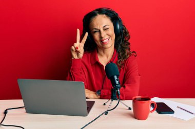 Güzel orta yaşlı kadın radyo stüdyosunda çalışıyor. Gülümsüyor, kameraya göz kırpıyor ve zafer işareti yapıyor. İki numara.. 