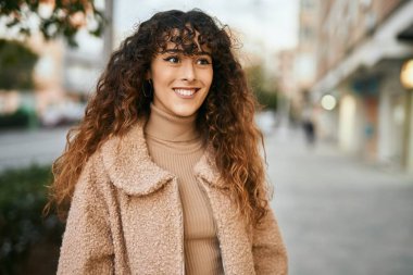 Genç İspanyol kadın gülümseyerek şehirde mutlu mesut dikiliyor.