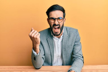 Ofiste kızgın ve kızgın çalışan genç bir İspanyol öfkeyle bağırırken yumruğunu kaldırıyor ve öfkeliydi. öfke ve agresif konsept. 