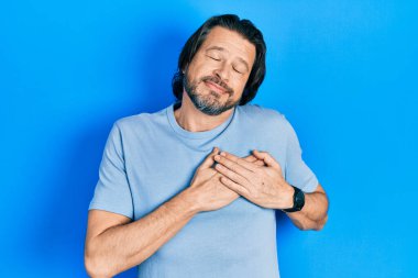 Orta yaşlı, sıradan kıyafetler giyen, göğsünde elleri kapalı, yüzünde minnet ifadesi olan beyaz bir adam. sağlık kavramı. 