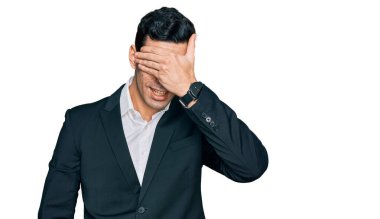 İş kıyafetleri giymiş yakışıklı İspanyol bir adam. Gülümsüyor ve elleri yüzünde, şaşırtmak için gözlerini kapatıyor. kör kavram. 