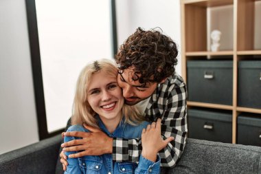 Kanepede oturan genç çift evde sarılıyorlar..