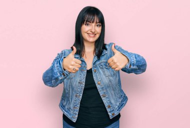 Latin kökenli genç bir kadın, günlük giysiler giyip, olumlu jestler yapıyor, gülümsüyor ve başarı için seviniyor. kazanan jest. 