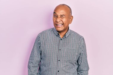 Orta yaşlı, sıradan kıyafetler giyen, kameraya seksi bir ifadeyle bakan, neşeli ve mutlu yüzlü bir Latin.. 