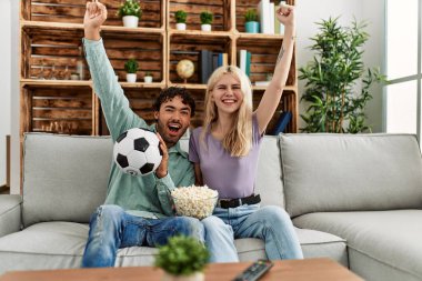 Genç bir çift futbol maçı izleyip evde mısır yiyor..