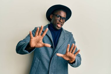 Zarif tarzda giyinen genç Afro-Amerikalı adam korku ifadesinden korkuyor ve dehşete düşüyor. El hareketlerini durdur, şok içinde bağır. panik konsepti. 