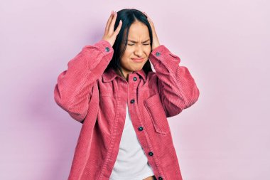 Burun piercingli güzel bir İspanyol kadın. Sıradan pembe bir ceket giyiyor. Baş ağrısı, çaresiz ve stresli. Eller başının üstünde.. 