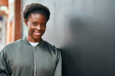 Genç Afrikalı Amerikalı kız gülümseyerek şehirde mutlu mesut duruyor..