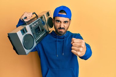 Kasetçalar tutan genç İspanyol bir adam. Sinirli ve sinirli bir şekilde bağırarak müzik dinliyor. Öfkeyle bağırıyor ve el kaldırıyor. 