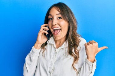 Genç esmer kadın akıllı telefonda konuşurken çok mutlu ve heyecanlı bir şekilde kollarını kaldırıp, gülümseyerek ve başarı çığlıkları atarak kazanan hareketi yapıyor. kutlama konsepti. 