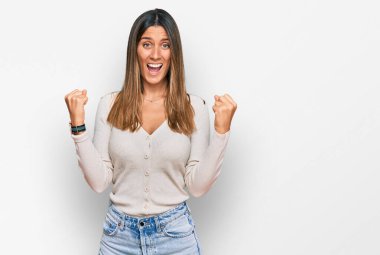 Gündelik giysiler giyen genç bir kadın şaşkınlık ve şaşkınlık içinde kollarını kaldırarak ve gözlerini açarak başarıyı kutluyor. Kazanan konsept. 