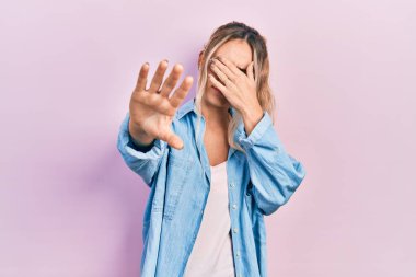 Güzel, genç, sarışın bir kadın. Günlük kıyafetler ve gözlük takıyor. Gözlerini elleriyle kapatıyor. utangaç ve olumsuz kavram. 