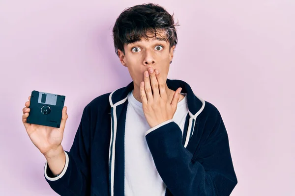 Bonito Jovem Hipster Segurando Disquete Cobrindo Boca Com Mão Chocado — Fotografia de Stock