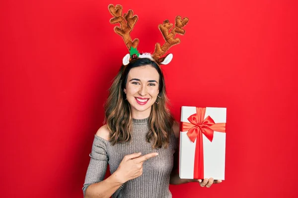 Joven Chica Hispana Con Sombrero Navidad Ciervo Sosteniendo Regalo Sonriendo —  Fotos de Stock