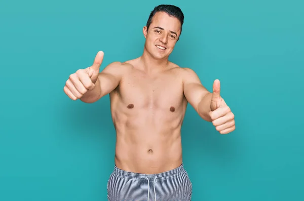 Przystojny Młody Człowiek Strojach Kąpielowych Bez Koszuli Aprobujący Pozytywne Gesty — Zdjęcie stockowe