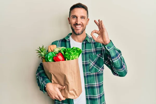 Hombre Guapo Con Barba Sosteniendo Bolsa Papel Con Comestibles Sonriendo —  Fotos de Stock