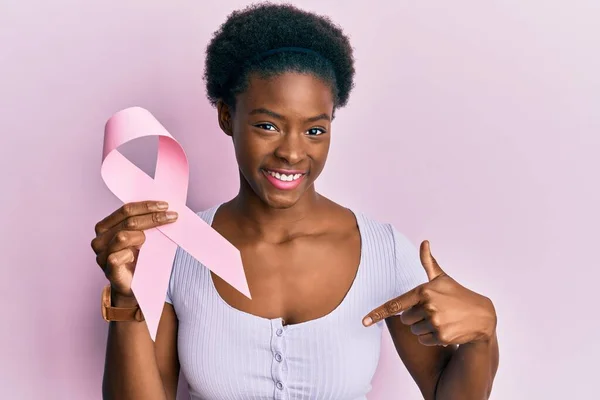若いですアフリカ系アメリカ人の女の子保持ピンク癌リボン指して指へ1自己笑顔幸せと誇り — ストック写真
