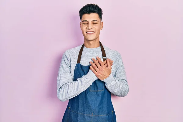 Jovem Hispânico Vestindo Avental Sorrindo Com Mãos Peito Com Olhos — Fotografia de Stock