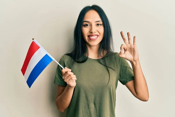 年轻的惊慌失措的女孩举着荷兰国旗 手拿着手签 微笑着表示友善的手势 是个极好的象征 — 图库照片