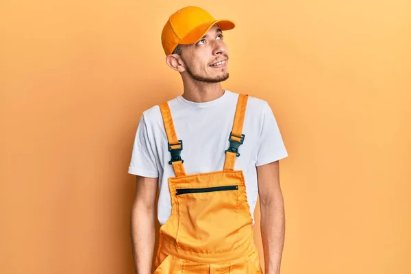 Hispanic Ung Man Bär Hantverkare Uniform Tittar Bort Till Sidan — Stockfoto