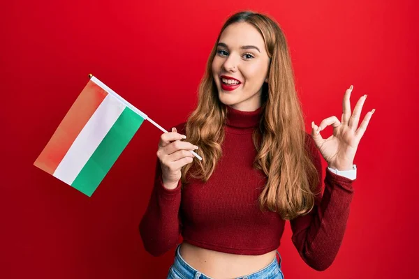 Νεαρή Ξανθιά Γυναίκα Κρατώντας Ουγγρική Σημαία Κάνει Υπογράψει Δάχτυλα Χαμογελώντας — Φωτογραφία Αρχείου