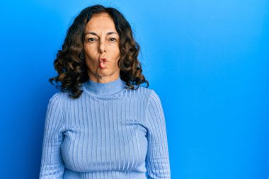 Orta yaşlı İspanyol kadın gündelik kıyafetler giyip dudaklarıyla balık suratı yapıyor, çılgınca ve komik hareketler yapıyor. Komik ifade. 