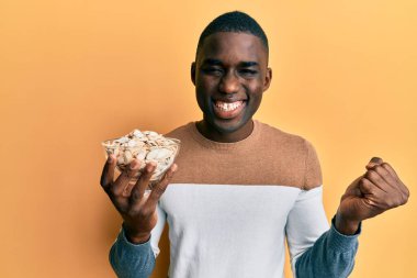 Genç Afrikalı Amerikalı adam elinde balkabağı tohumlarıyla gururla bağırıyor zaferi ve başarıyı kutluyor. 