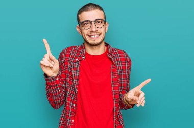 Gündelik giysiler giyen İspanyol genç adam gülümseyerek farklı yönleri işaret ederek kendine güveniyor. reklam için kopyalama alanı 