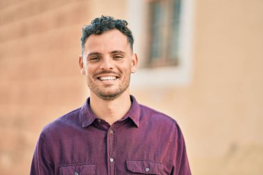 Genç İspanyol adam gülümseyerek şehirde mutlu mesut dikiliyor..