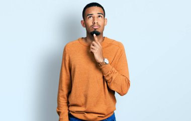 Genç, Afro-Amerikan bir adam günlük kıyafetler giyiyordu. Kuşku üzerine yoğunlaşmıştı. Parmakları çenesinde ve yukarı bakıyordu. 