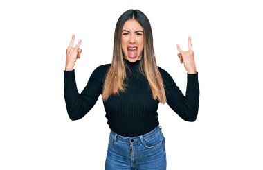 Genç İspanyol kadın gündelik kıyafetler giyip çılgın bir ifadeyle bağırıyor ve elleri havada rock sembolü yapıyor. Müzik yıldızı. ağır kavram. 