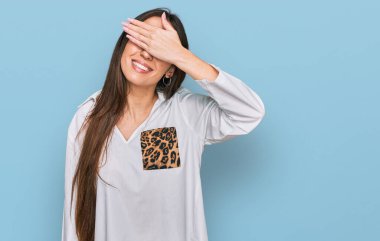 Günlük kıyafetler giyen, gülümseyen ve gülen genç İspanyol kız şaşırmak için gözlerini kapatıyor. kör kavram. 