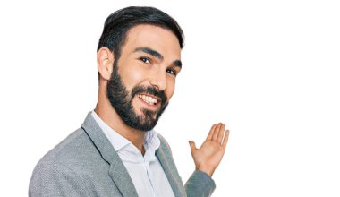 Latin kökenli genç adam iş kıyafetleri içinde gülümseyerek içeri girmeye davet ediyor. 