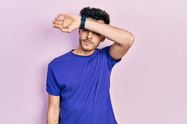 Gündelik tişört giyen genç İspanyol adam kollarıyla gözlerini kapatıyor, ciddi ve üzgün görünüyor. Görme, saklama ve reddetme konsepti 