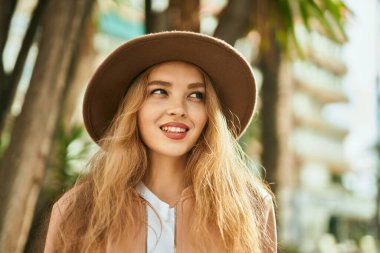 Genç sarışın kız gülümsüyor, mutlu bir şekilde şehirde duruyor..