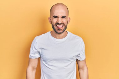 Sıradan beyaz tişört giyen genç kel adam komik bir ifadeyle dilini dışarı çıkartıyor. duygu kavramı. 