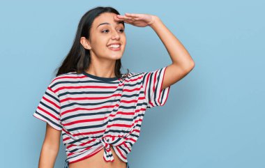 Genç İspanyol kız gündelik giysiler giyiyor çok mutlu ve gülümsüyor başlarını kaldırıp uzaklara bakıyor. arama kavramı. 