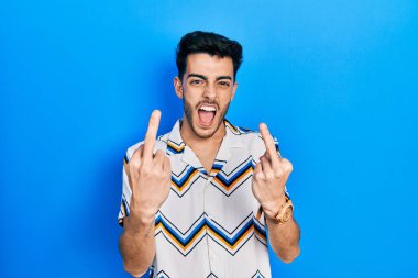 Young hispanic man wearing casual clothes showing middle finger doing fuck you bad expression, provocation and rude attitude. screaming excited 