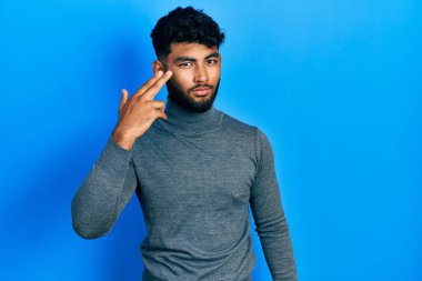 Balıkçı yaka kazak giyen sakallı bir Arap, kendini ve parmaklarını silah gibi göstererek vuruyor, intihar ediyor.. 