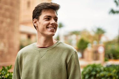 Genç İspanyol adam gülümseyerek şehirde mutlu mesut dikiliyor..